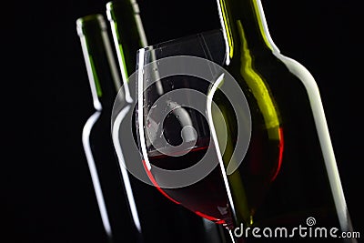 Bottles and glass of red wine on a black background . Stock Photo