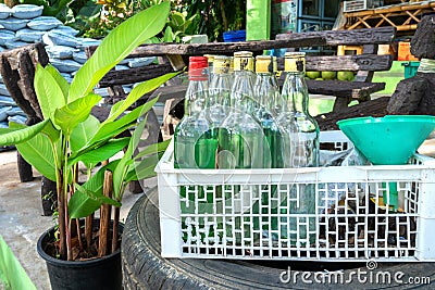 Bottles of green gasoline for sale to motorcyclists in a fruit crate. Illegal sale of petroleum products to tourists in Thailand Editorial Stock Photo