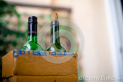 Bottles of liquor alcohol in a cardboard box getting home delivered online kept in the garden at the threshold of a home Editorial Stock Photo