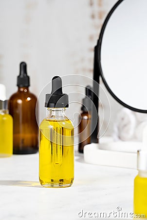 Bottles with serum oils and mirror on the cosmetic table in the bathroom. A set of organic cosmetics in glass vials with dropper Stock Photo