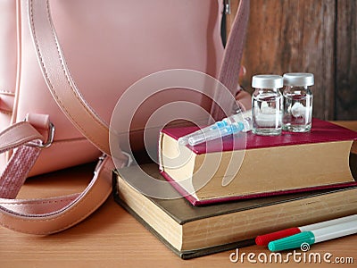Bottles and syringes of vaccine aganist covid-19 near book pile and school supplies, children vaccination concept Stock Photo