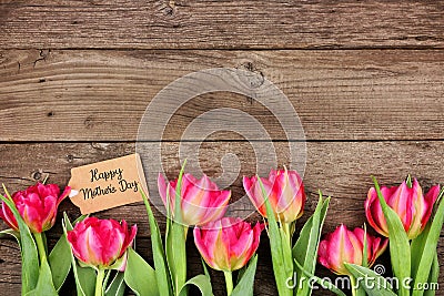 Happy Mothers Day tag with bottom border of pink flowers against a rustic wood background Stock Photo