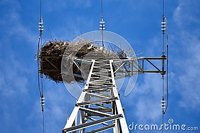 empty bird nest made with branches of trees at the top of an electrical tower of high voltage that conducts electricity to houses Stock Photo