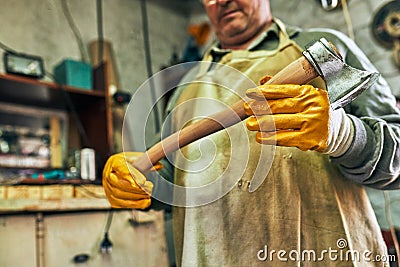 Bottom view image of an adult craftsman manufacturing in his workshop. Professional senior worker man looking to the the hatchet Stock Photo