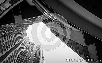 Bottom view of skyscraper building against gray sky and clouds. Looking up view in apartment building in the city. Real estate Stock Photo
