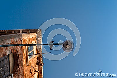 Bottom view of Traditional street lamp with a sitting dove bird looking to the camera at an old Venetian house in the Stock Photo