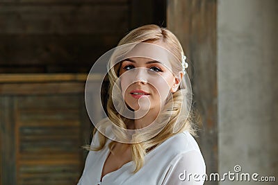 Boudoir photo of the bride in the morning. A beautiful portrait of a young blonde woman in a white coat sitting by the window Stock Photo