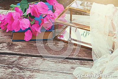 bougainvillea flower, delicate scarf and glass box on old wooden table outdoor in the park Stock Photo