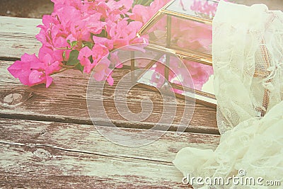 bougainvillea flower, delicate scarf and glass box on old wooden table outdoor in the park Stock Photo