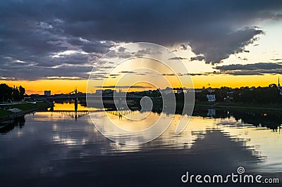 Mesmerizing blazing sunset over the mirror glossy surface of the Volga river, reflecting dramatic sky. City of Tver, Russia. Stock Photo