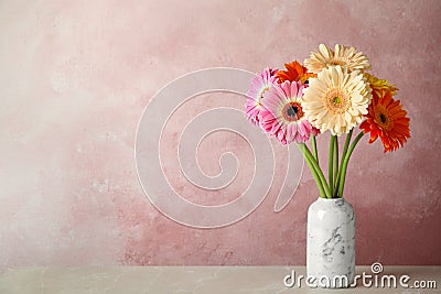 Bouquet of beautiful bright gerbera flowers in vase on marble table against color background. Stock Photo