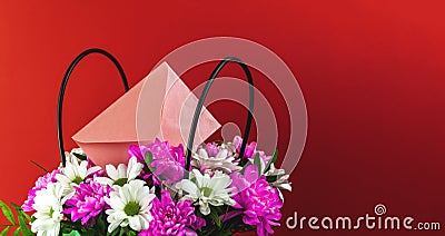Bouquet of beautiful spring flowers in basket with love envelop, festive and holiday banner with copy space on red background Stock Photo