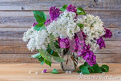 Bouquet of colorful lilac flowers in a glass vase on a wooden background Stock Photo