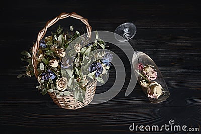 A bouquet of dried flowers and a fallen glass with petals is a concept of alcohol problems and life difficulties Stock Photo