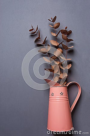 Bouquet of Dry Red Orange Silver Dollar Eucalyptus in Vintage Metal Pink Jug on Grey Background. Flat Lay Creative. Website Banner Stock Photo
