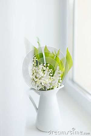 Bouquet of fresh spring lilies of the valley in a white jug on t Stock Photo