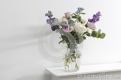 Bouquet of hackelia velutina, purple and white roses, small tea roses, matthiola incana and blue iris in glass vase is on the Stock Photo