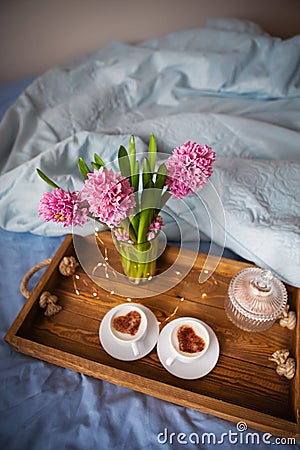 A bouquet of hyacinths, two cups of cappuccino stand on an old wooden tray Stock Photo