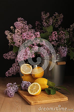 A bouquet of lilacs in a bucket. Still life in the Flemish style. Lemons. Spring. Still life in a low key. Stock Photo