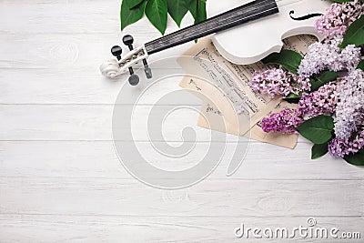 A bouquet of lilacs with violin and music sheet on a white wooden table. Top wiev with space for your text Stock Photo