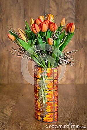 Bouquet of orange tulips in glass colorful vase Stock Photo