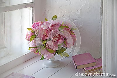Bouquet of orchids, peonies, roses in a ceramic vase and a stack of books Stock Photo