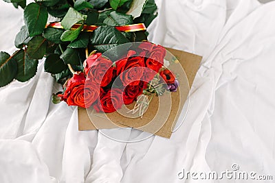 A bouquet of red roses, envelope with congratulation on a background of linen Stock Photo