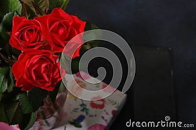 Bouquet red roses flower in glass vase on dark background and black smartphone no focus, gift box Stock Photo