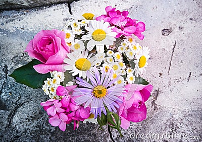 Bouquet of roses, geranium, daisies on a concrete wall with a crack Stock Photo