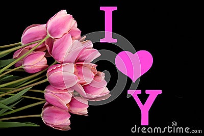 A bouquet of soft pink tulips, English letters and a heart of bright pink on a black background. Expression I LOVE YOU. Concept of Stock Photo