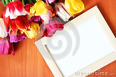 Bouquet of tulips and white mockup frame on wooden background. Easter or Birth Day greeting mock up. Stock Photo