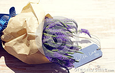 Bouquet of violet wild summer flowers and the blue card with the inscription With love on the wooden background Stock Photo