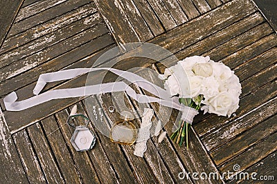 Bouquet of white roses with a long developing ribbon for the bride with garter, perfume bottle, wedding ring, earrings Stock Photo