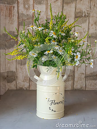 Bouquet of wildflowers in a high pale yellow metal planter on a gray table Stock Photo