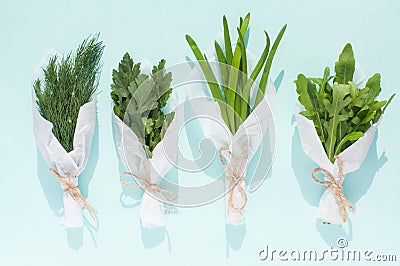 Bouquets of fresh greens for salad packed in white paper on a light blue background isolated Stock Photo