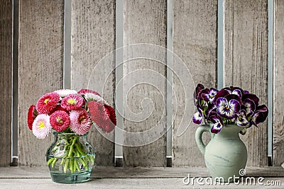 Bouquets of pansy and daisy flowers in ceramic vases. Wooden background Stock Photo