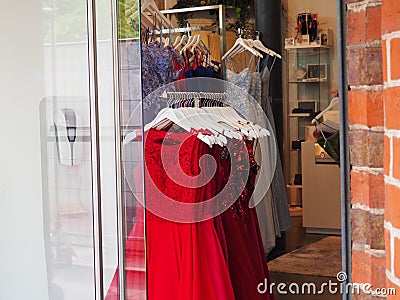 Boutique store window display with an array of vibrant red dresses suspended from a sleek metal rack Editorial Stock Photo