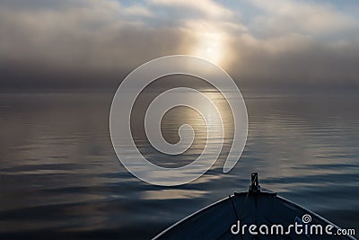 Bow of aluminum fishing boat at sunrise on foggy lake Stock Photo