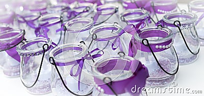 Bow-tied purple ribbons on glass candle holders. Stock Photo