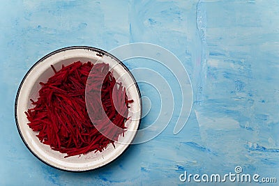 Bowl of beetroot cut into thin strips on blue painted wooden background. Vegetarian, organic, healthy food, diet, nutrition. Top Stock Photo