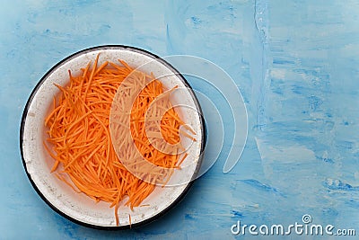 Bowl of carrots cut into thin strips on blue painted wooden background. Vegetarian, organic, healthy food, diet, nutrition. Top Stock Photo