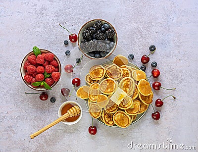 Bowl with cereal tiny pancake with berries and maple syrup. Stock Photo