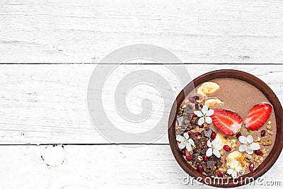 Bowl of cocoa smoothie with chocolate granola, banana, strawberry and pomegranate topped with flowers Stock Photo