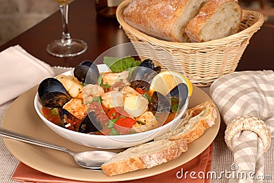 Bowl of delicious seafood soup with wine and rustic bread Stock Photo