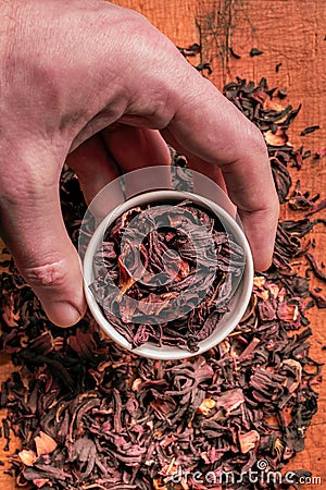 A bowl of dry hibiscus in a small bowl, male hand. A healthy herb for healthy life. Stock Photo