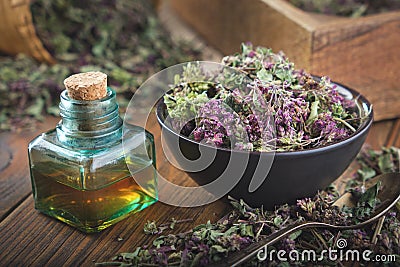 Bowl of dry Origanum vulgare or wild marjoram flowers. Bottle of essential oil or infusion Stock Photo