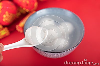 A bowl of dumplings or Yuanxiao on a festive red background with a spoon Stock Photo