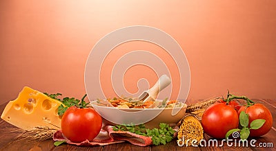 A bowl of farfalle and wooden scoop, bunch of spaghetti, tomatoes, cheese, parsley, basil and tea towel on red. Stock Photo