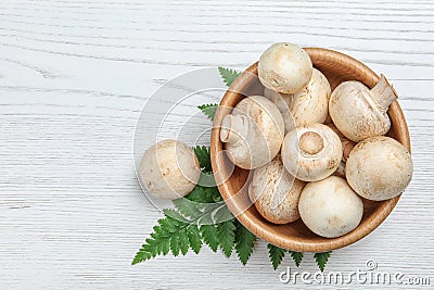 Bowl of fresh champignon mushrooms on wooden background, top view Stock Photo