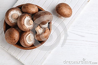 Bowl with fresh champignon mushrooms on wooden table, top view. Stock Photo